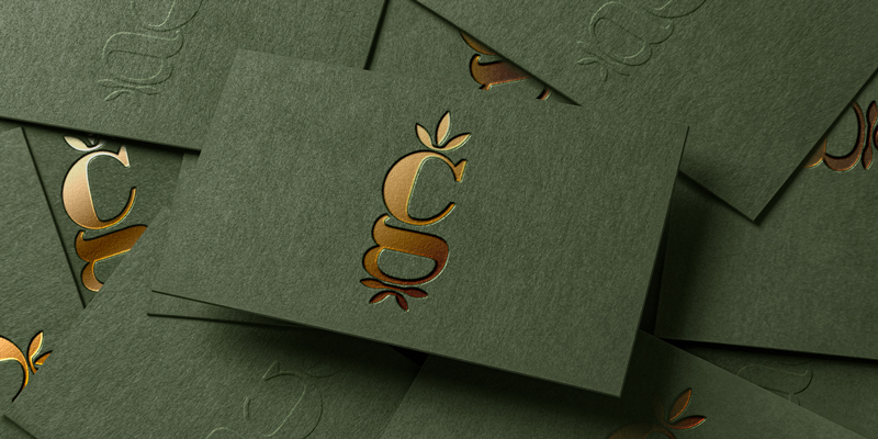 Premium business card design for Cornucopia Growers featuring textured olive green stock with embossed lettering and copper foil logo branding.