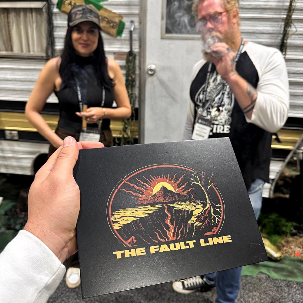 The Fault Line cigar packaging artwork displayed at a Wildfire Cigars trade show booth, featuring custom branding and promotional design by Hellbeing Agency.